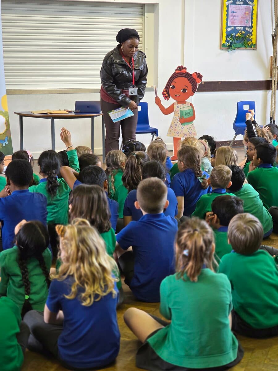Tinu presenting at a school assembly with Lola banner